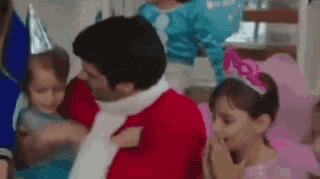a man in a santa suit is sitting next to a group of children .
