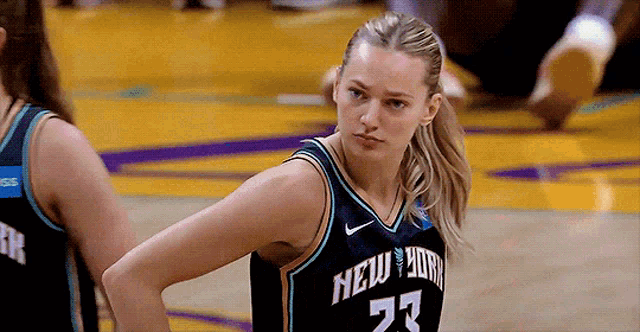 a woman in a new york jersey stands on a court