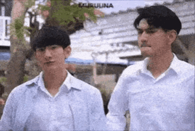 two men in white shirts are standing next to each other in a park .