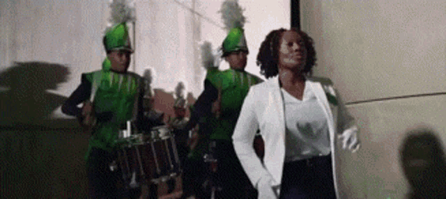 a woman in a white jacket is walking in front of a marching band