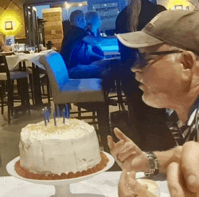 a man is sitting at a table with a cake and candles in front of him