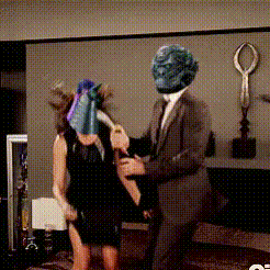 a man in a suit is holding a woman in a black dress with a mask on her face