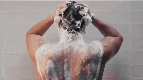 a man is taking a shower with foam on his back .
