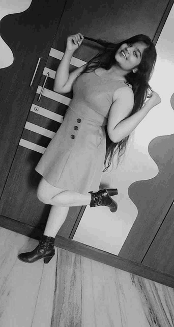 a black and white photo of a woman standing in front of a wardrobe