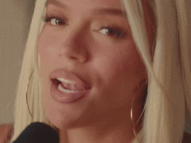 a blonde woman is singing into a microphone and making a funny face