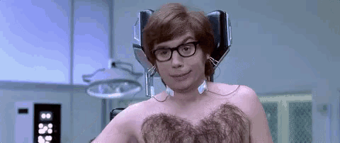 a shirtless man with hair on his chest is sitting in an operating room with a machine .