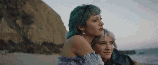 a woman with green hair is hugging another woman