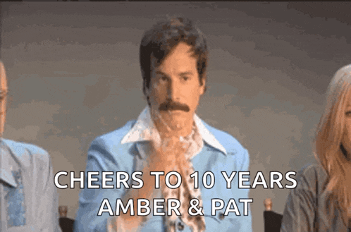 a man with a mustache is sitting in front of a group of people and says cheers to 10 years amber & pat