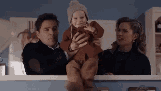 a man and a woman are holding a baby in their arms in a room .