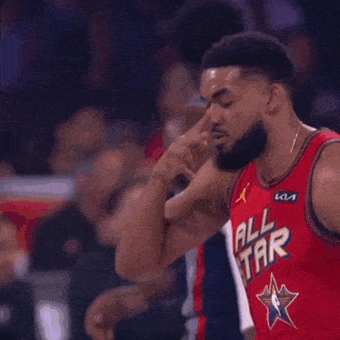 a basketball player wearing an all star jersey is making a peace sign with his hand .