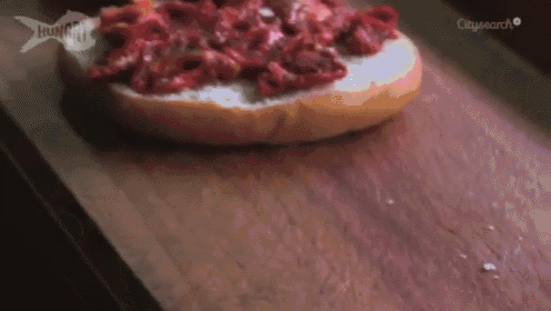a bun with meat on it is on a wooden cutting board with citysearch written on the bottom