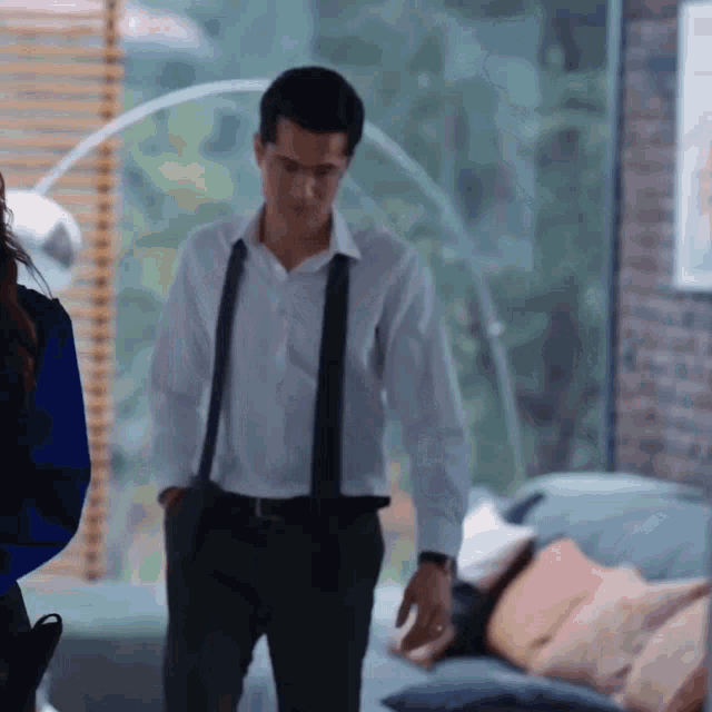 a man in a white shirt and black suspenders is walking in a living room