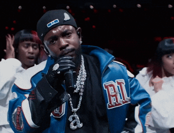 a man singing into a microphone wearing a jacket that has the letter b on it
