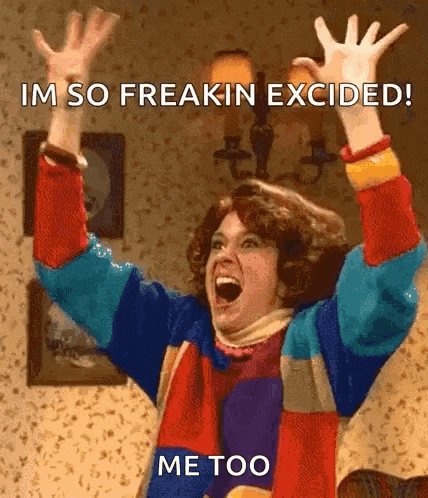 a woman in a colorful sweater is screaming with her arms in the air and says im so freakin excited me too