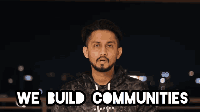 a man stands in front of a sign that reads we build communities