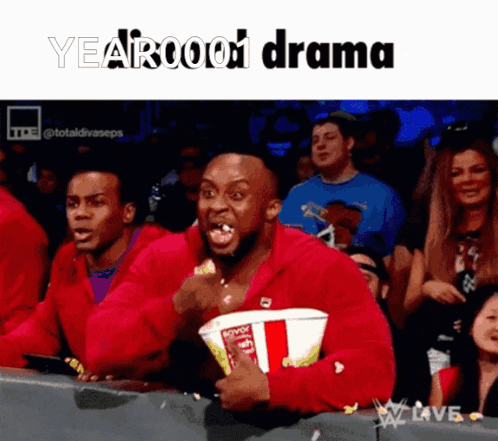 a man in a red jacket is eating popcorn and watching a yearbook drama