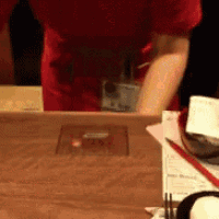 a person in a red shirt is standing in front of a table
