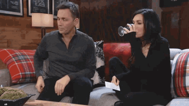 a man and a woman are sitting on a couch looking at a cell phone
