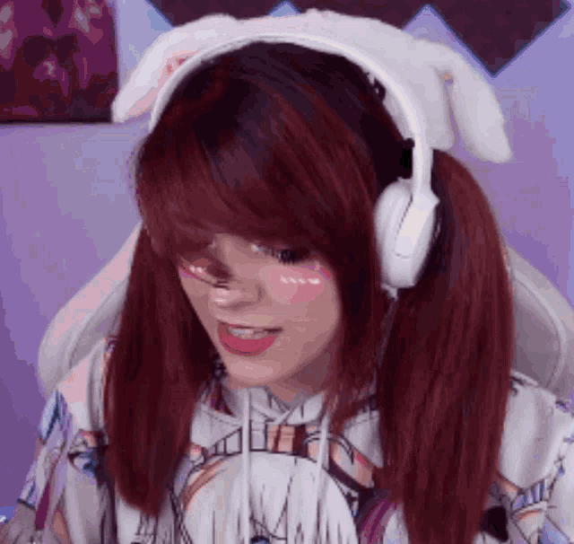 a girl with red hair wearing white headphones and a hoodie