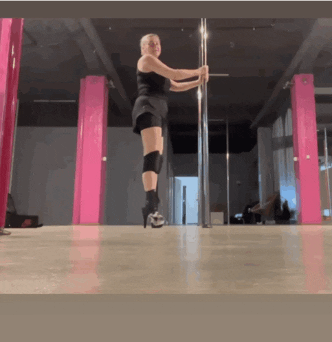 a woman is standing on a pole in a room with pink pillars