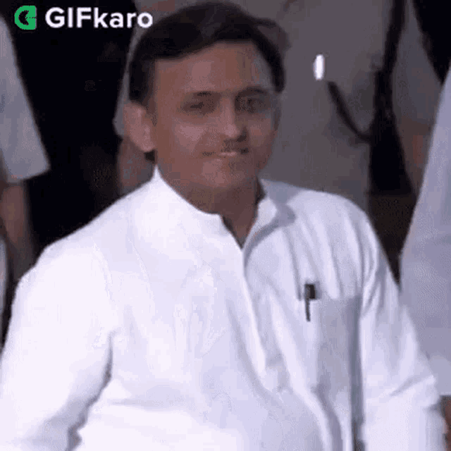 a man in a white shirt with a pen in his pocket is standing in front of a crowd .