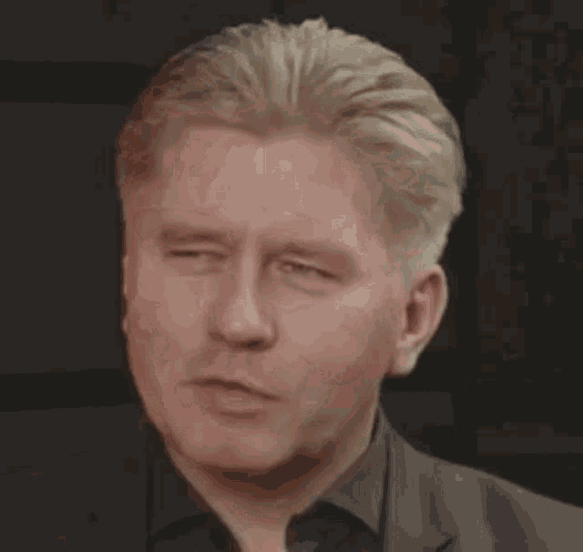 a man with blonde hair is smiling and wearing a black shirt