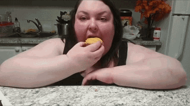 a woman is sitting at a counter eating a piece of food .