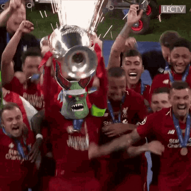 a group of soccer players are holding up a trophy and one of them has a mask on
