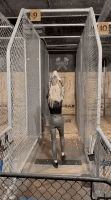a woman is throwing an axe in a cage at an axe throwing event .