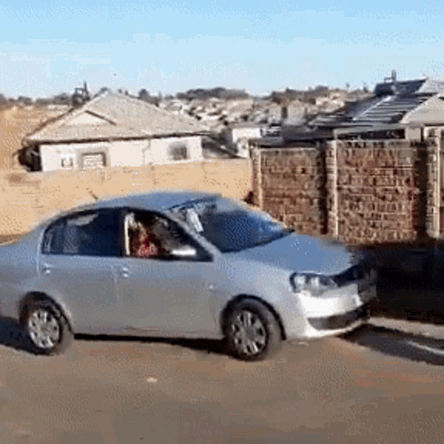 a silver car is parked in front of a brick building