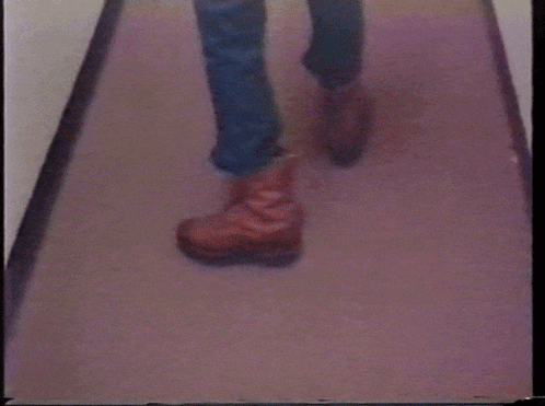 a person is walking down a hallway with a pair of brown boots on