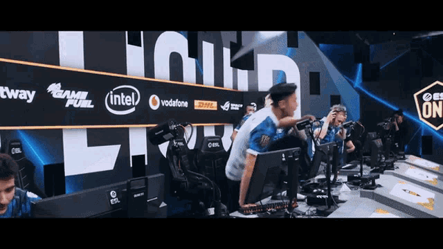 a group of people sitting in front of a wall that has intel vodafone and dhl logos on it