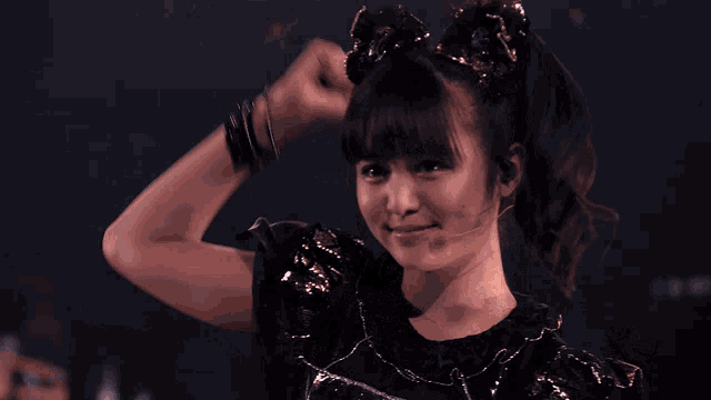 a girl with a ponytail and bracelets on her wrists holds her fist in the air