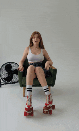 a woman sits in a chair holding a roller skate in front of her face