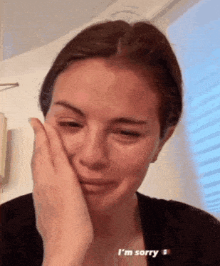 a woman is crying and covering her face with her hand and the caption says i 'm sorry .
