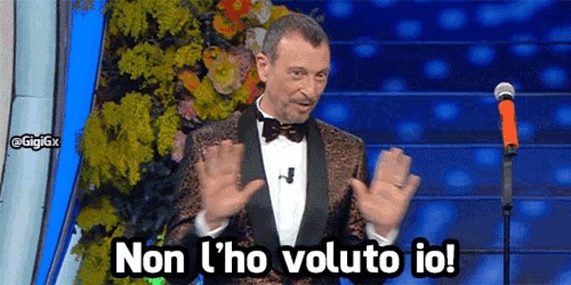 a man in a tuxedo stands in front of a microphone with the words non l' ho voluto io