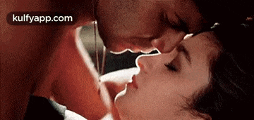 a man is kissing a woman on the forehead while laying on a bed .