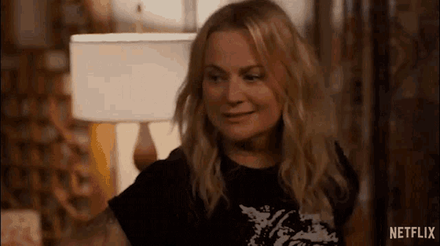 a woman in a black t-shirt is sitting in a living room .
