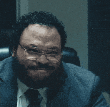 a man wearing glasses and a suit has the words semi-gloss above him