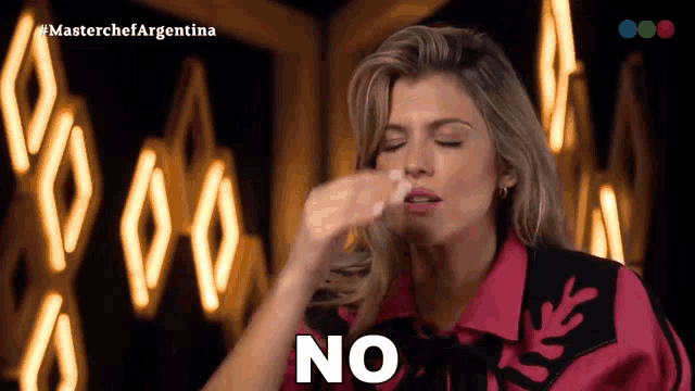 a woman in a pink shirt says " no " in front of a neon sign
