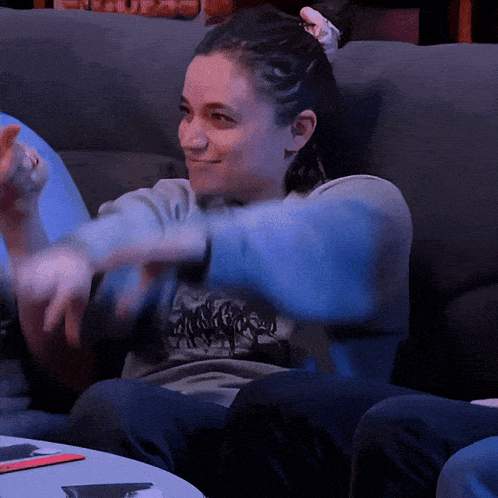 a woman is sitting on a couch with her hands outstretched