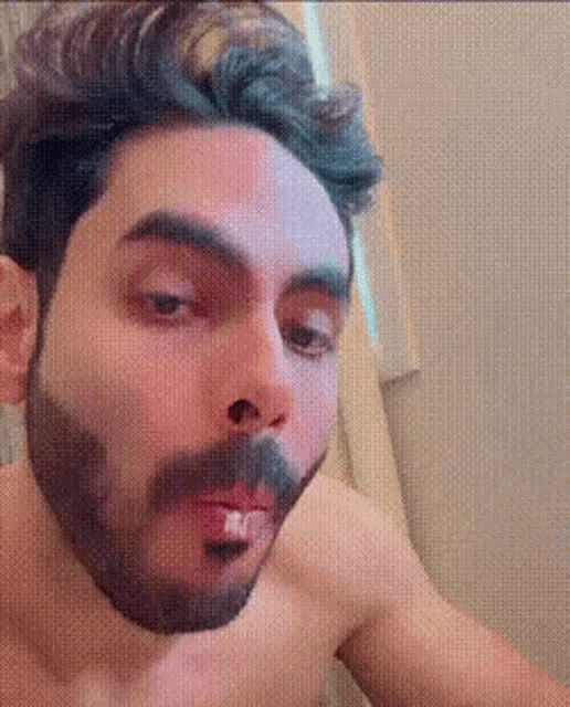 a man with a beard and mustache is brushing his teeth .