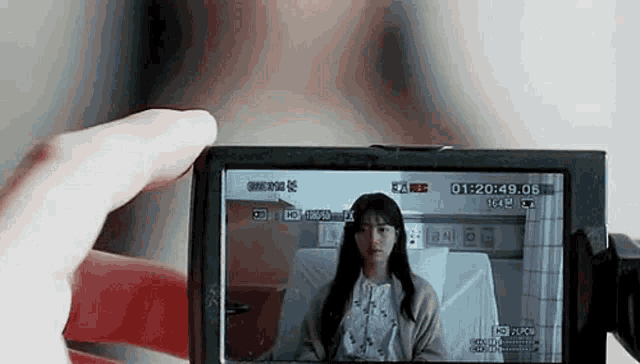 a person is holding a camera with a woman in a hospital bed on the screen .