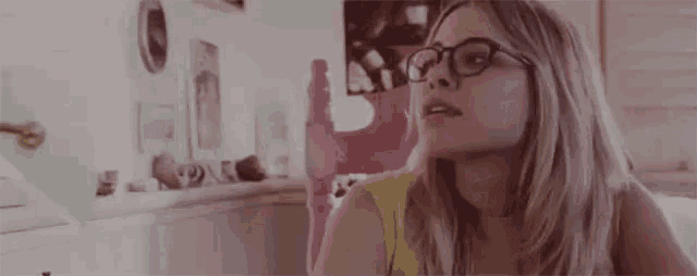a woman wearing glasses and a yellow shirt is looking up