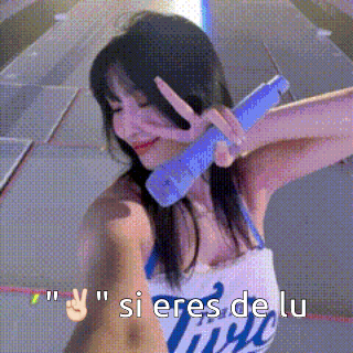 a woman is holding a blue microphone and giving a peace sign .