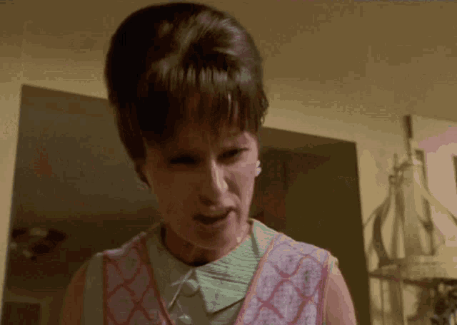 a woman wearing a pink apron and a green collar is making a face