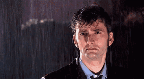 a man is crying in the rain while wearing a suit and tie .