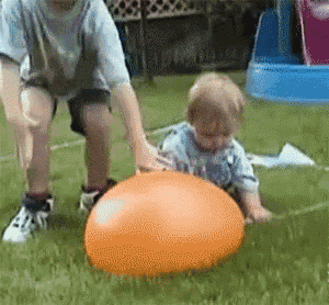 a boy and a baby are playing with an orange ball