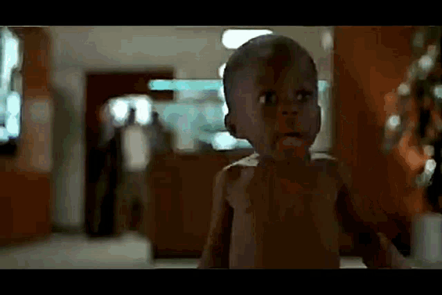 a baby without a shirt is walking in a hallway .