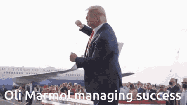 a man in a suit stands in front of an airplane with the words oli marmot managing success
